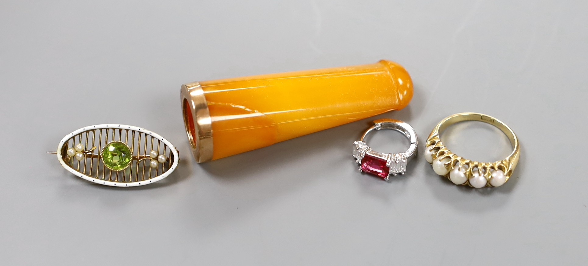 An 18ct and graduated cultured pearl set half hoop ring, size O/P, gross 5.2 grams, an Edwardian yellow metal, enamel, seed pearl and peridot brooch, an amber cig holder and a paste set clip?